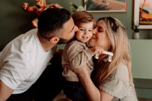 Des parents qui embrassent leur fils dans leur maison lors d'une séance photo en provence. Ils sont en tenue décontractée avec des couleurs qui s'accordent