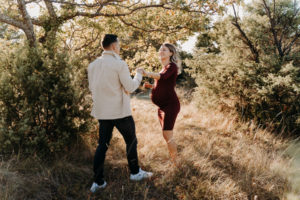 Jeune couple de futurs parents dansant de bonheur dans la nature près de Carpentras en Provence. Habillée enrobe bordeaux, couleurs qui se mlarie bien dans la campagne provencale